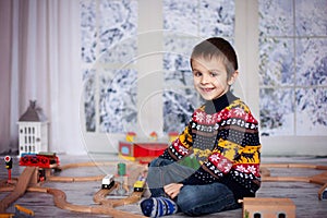 Adorable little preschool boy, playing with wooden trains and ra