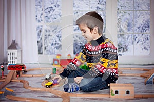 Adorable little preschool boy, playing with wooden trains and ra