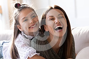 Adorable little school girl daughter cuddling laughing mommy.