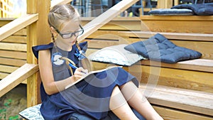 Adorable little school girl with notes and pencils outdoor. Back to school.