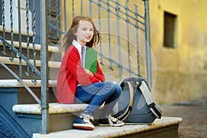 Adorable little schoolgirl studying outdoors on bright autumn day. Young student doing her homework. Education for small kids.