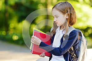 Adorable little schoolgirl studying outdoors on bright autumn day. Young student doing her homework. Education for small kids.