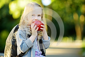 Adorable little schoolgirl studying outdoors on bright autumn day. Young student doing her homework. Education for small kids.