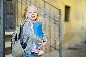 Adorable little schoolgirl studying outdoors on bright autumn day. Young student doing her homework. Education for small kids.