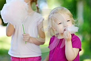 Adorable little sisters eating candy-floss
