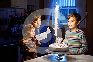 Adorable little toddler girl celebrating third birthday. Baby sister child and two kids boys brothers blowing together