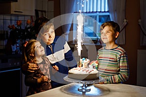 Adorable little toddler girl celebrating third birthday. Baby sister child and two kids boys brothers blowing together