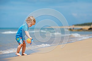 Adorable little toddler girl playing on sand beach