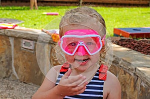 Adorable little toddler in pink goggles and swimsuit.