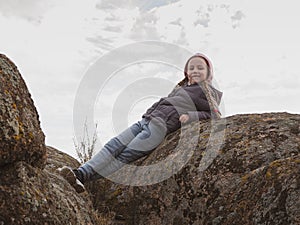 Adorable little traveler girl smiling. Child climbing on mountain summit spending time on nature walking enjoying scenic