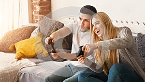 Adorable millennial couple playing video games together at home