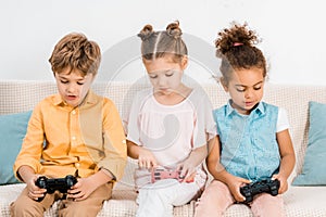 adorable multiethnic kids sitting on couch and playing