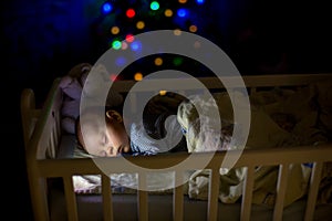 Adorable newborn baby boy, sleeping in crib at night
