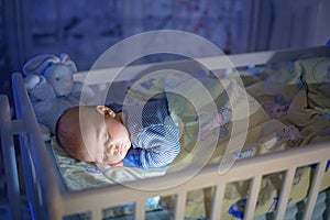 Adorable newborn baby boy, sleeping in crib at night photo