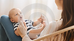 Adorable newborn baby cooing while lying on mother`s lap