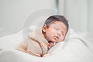 Adorable newborn baby peacefully sleeping on a white blanket.