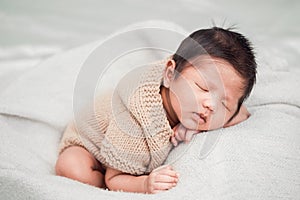 Adorable newborn baby peacefully sleeping on a white blanket.