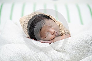 Adorable newborn baby peacefully sleeping on a white blanket.
