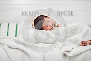Adorable newborn baby peacefully sleeping on a white blanket.