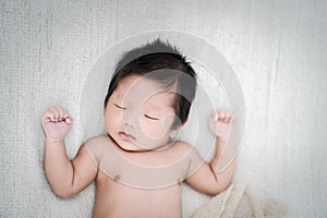 Adorable newborn baby peacefully sleeping on a white blanket, Top view.