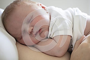 An adorable newborn baby sleeping on their mum