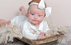 Adorable newborn girl lying on tummy on rug