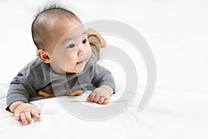 Adorable newborn kid during tummy time smiling happily at home.Portrait of cute smiling happy asian baby boy crawling on bed on