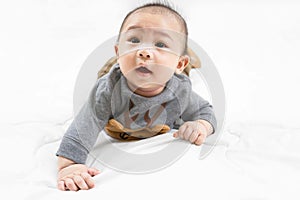 Adorable newborn kid during tummy time smiling happily at home.Portrait of cute smiling happy asian baby boy crawling on bed on