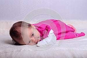 Adorable one month old baby girl in pink dress lies on a soft blanket