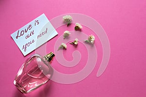 Adorable perfume with flower odor near peace of paper on pink background. Love concept. Gift for womans and valentines day. Copy