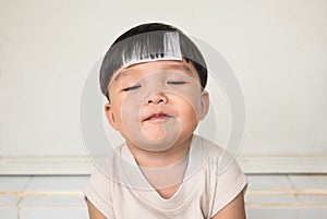 Adorable plump boy smilingly with chubby cheeked and close eyes. Front view of kid with illness