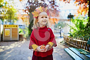 Adorable preschooler girl enjoying nice and sunny autumn day outdoors