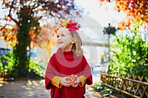 Adorable preschooler girl enjoying nice and sunny autumn day outdoors