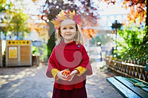 Adorable preschooler girl enjoying nice and sunny autumn day outdoors