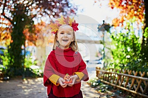 Adorable preschooler girl enjoying nice and sunny autumn day outdoors