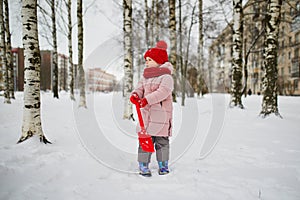 Adorable preschooler girl having fun in beautiful winter park on a snowy cold winter day