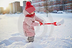 Adorable preschooler girl having fun in beautiful winter park on a snowy cold winter day