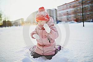 Adorable preschooler girl having fun in beautiful winter park on a snowy cold winter day