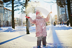 Adorable preschooler girl having fun in beautiful winter park on a snowy cold winter day