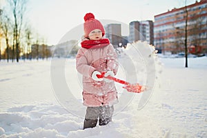 Adorable preschooler girl having fun in beautiful winter park on a snowy cold winter day