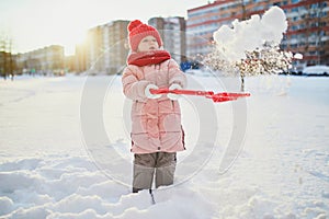 Adorable preschooler girl having fun in beautiful winter park on a snowy cold winter day