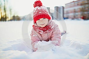 Adorable preschooler girl having fun in beautiful winter park on a snowy cold winter day