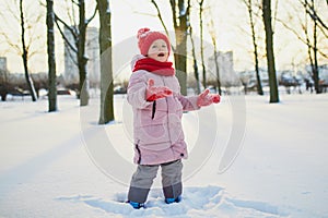 Adorable preschooler girl having fun in beautiful winter park on a snowy cold winter day