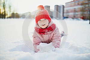 Adorable preschooler girl having fun in beautiful winter park on a snowy cold winter day