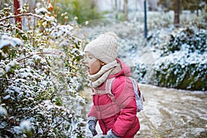 Adorable preschooler girl having fun in beautiful winter park on a snowy cold winter day