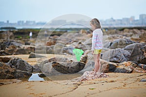 Adorable preschooler girl playing with scoop net on the beach at Atlantic coast of Brittany, France