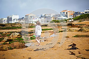 Adorable preschooler girl playing with scoop net on the beach at Atlantic coast of Brittany, France