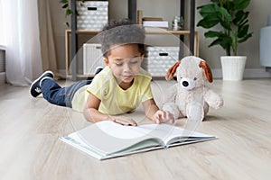 Adorable preschooler mixed race child boy reading book at home