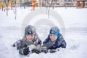 Adorable preschooler in winter wear sit amoung snow and play wit