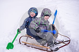 Adorable preschooler in winter wear sit amoung snow and play wit